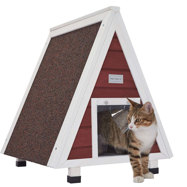 Red panel A-frame wooden cat house with white trim, elevated feet, and transparent door flaps, with a tabby cat at entry.