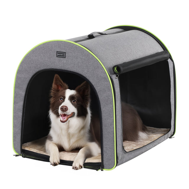 Smiling brown and white dog rests inside a roomy soft dog crate, with front opening and side panel for airflow and comfort.
