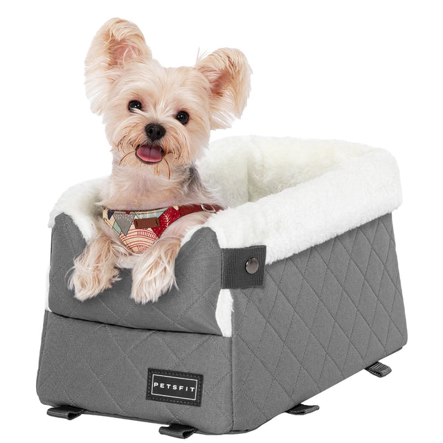 Close-up of a small terrier in a gray booster seat for dogs, featuring diamond stitching and a thick soft rim.