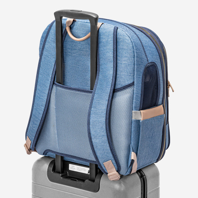 Rear view of the carrier secured on a rolling suitcase handle, highlighting luggage strap and breathable padded back panel.