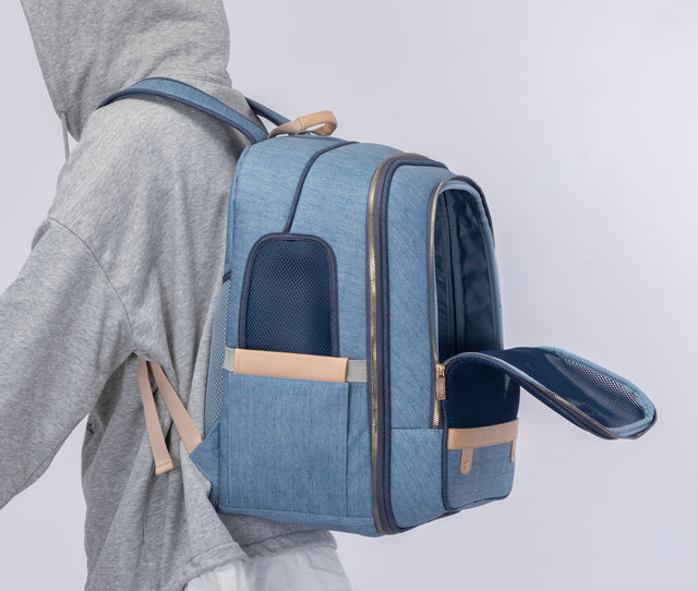 Person in a hoodie wearing the backpack with front mesh door open, demonstrating hands-free commuting with pet access.