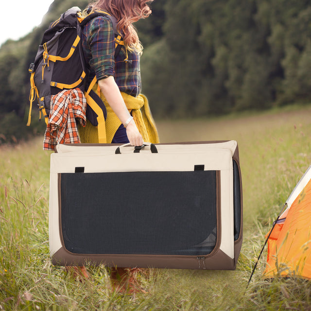 Hiker carries a folded travel dog crate across a grassy campsite near a tent, showing portability for outdoor adventures.