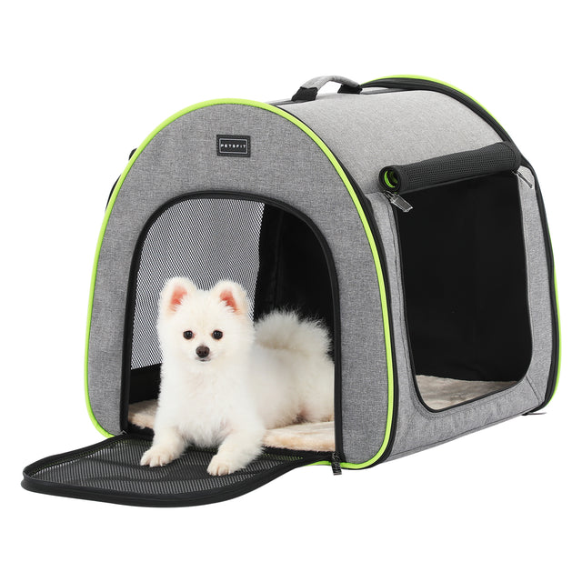 Fluffy white puppy lounges at the open entrance of a gray soft dog crate with breathable mesh panels and cushioned mat.