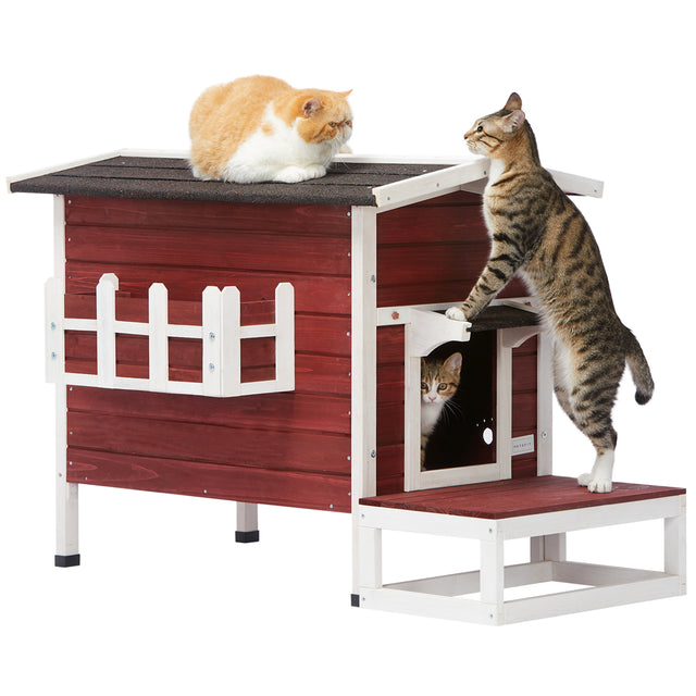 Three cats use the outdoor cat house at once, with one inside, one climbing the step, and one resting comfortably on the roof.