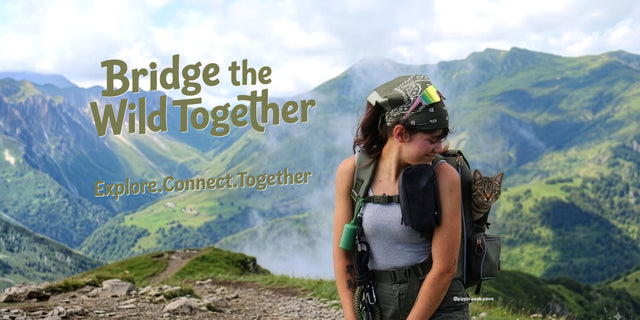Hiker in a bandana carries a tabby cat in an olive pet backpack on a green alpine ridge above misty valleys
