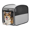 Smiling corgi relaxes at the open doorway of a gray pop-up dog crate with breathable mesh sides and a roll-up front flap.
